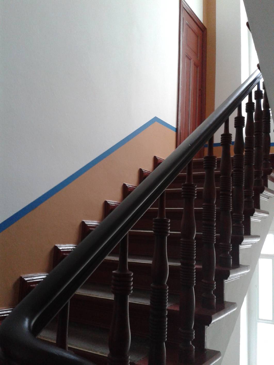 Der Sockel im Treppenhaus aus dem Jugendstil wurde tiefer gesetzt und gibt dem Treppenhaus mehr Höhe. Der Begleitstrich in Koboldblau ist komplementär zu den in Ochsenblut gehaltenen Holzbauteilen.  Mein Unternehmen Malermeister u. staatl. gepr. Techniker Norbert Schimpf führt Restaurierung -en, Gestaltung -en und Malerarbeiten aus. Wir haben uns auf Treppenhäuser spezialisiert.